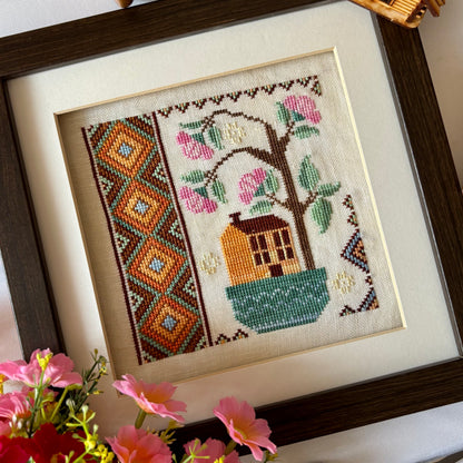 Cross stitch pattern of a whimsical house with a blooming rose tree – Rose Tree House design