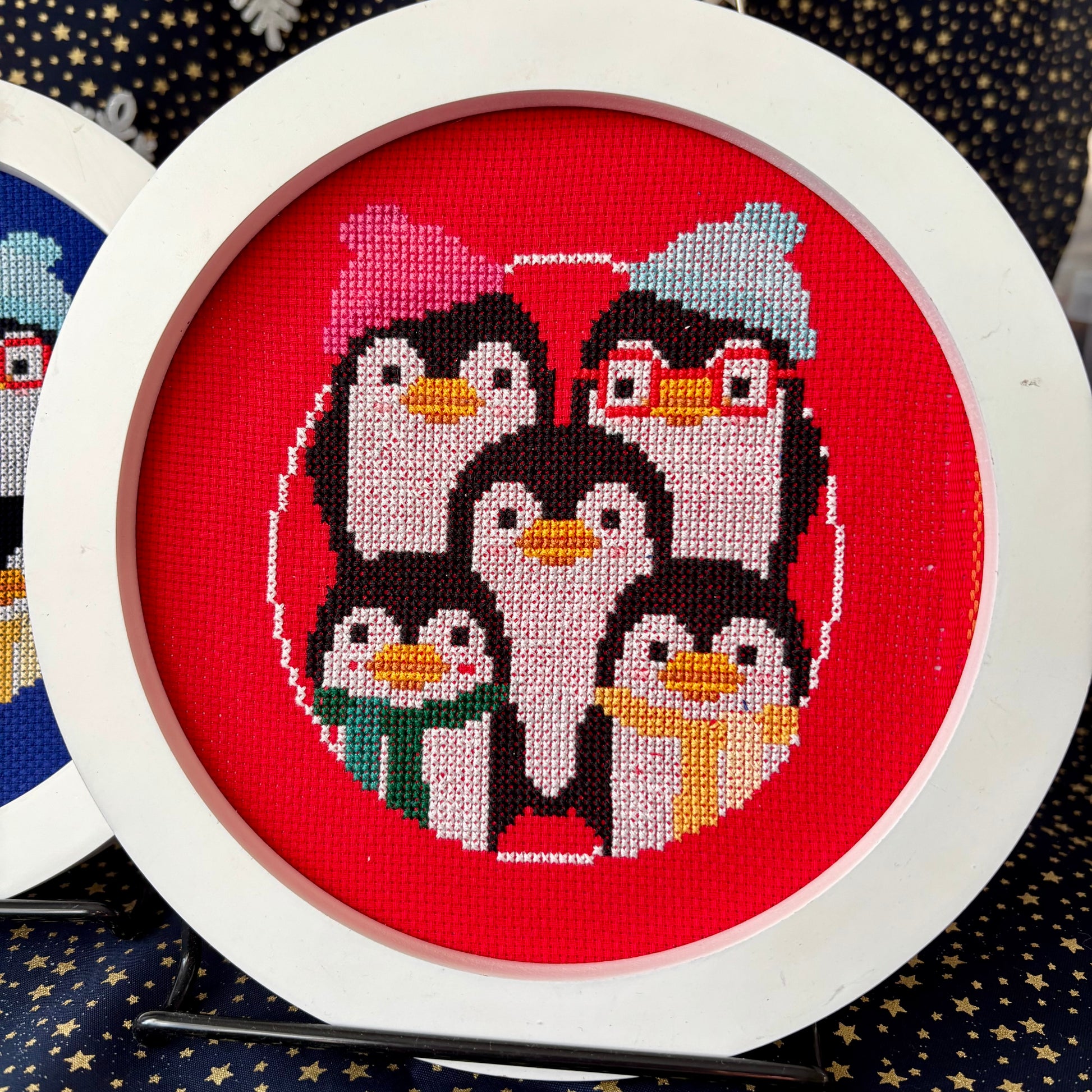 Cross-stitched penguins on a red background with a white frame.