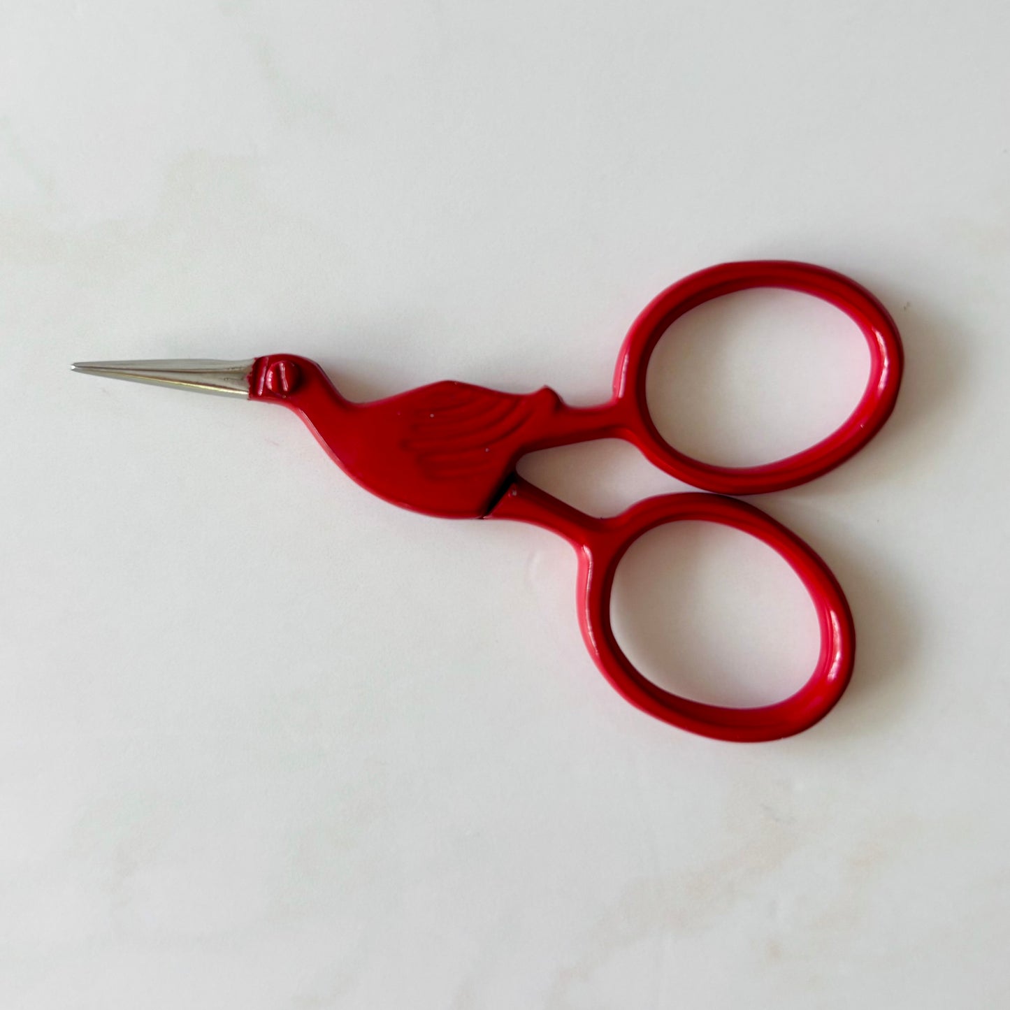 Red embroidery scissors on a white background