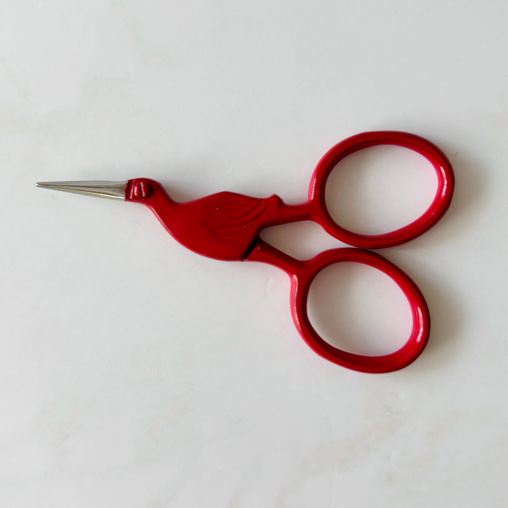 Red embroidery scissors on a white background
