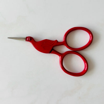 Red embroidery scissors on a white background