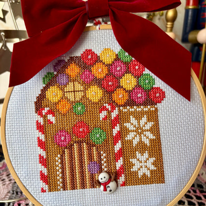 Embroidery hoop with a gingerbread house design and red ribbon