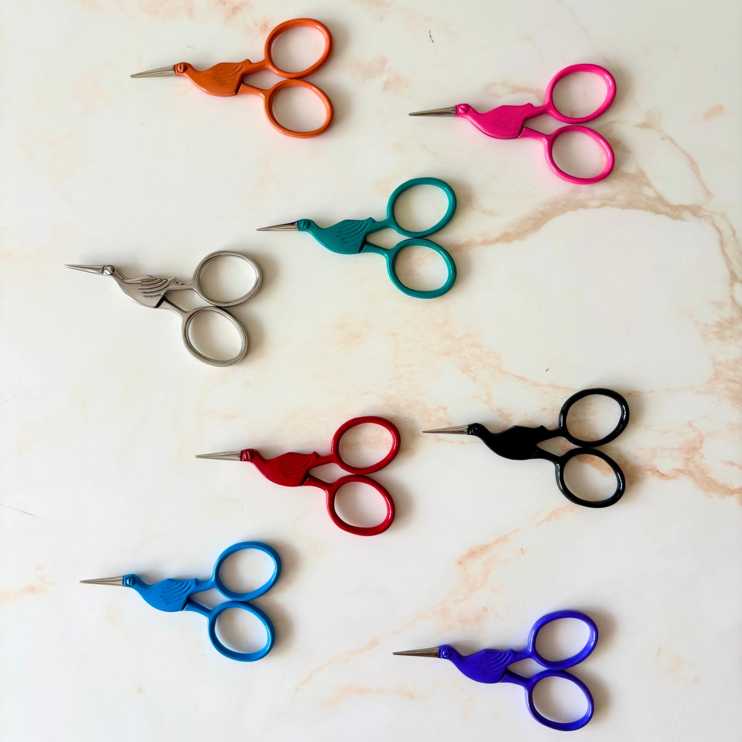 Assorted colorful scissors on a marble surface