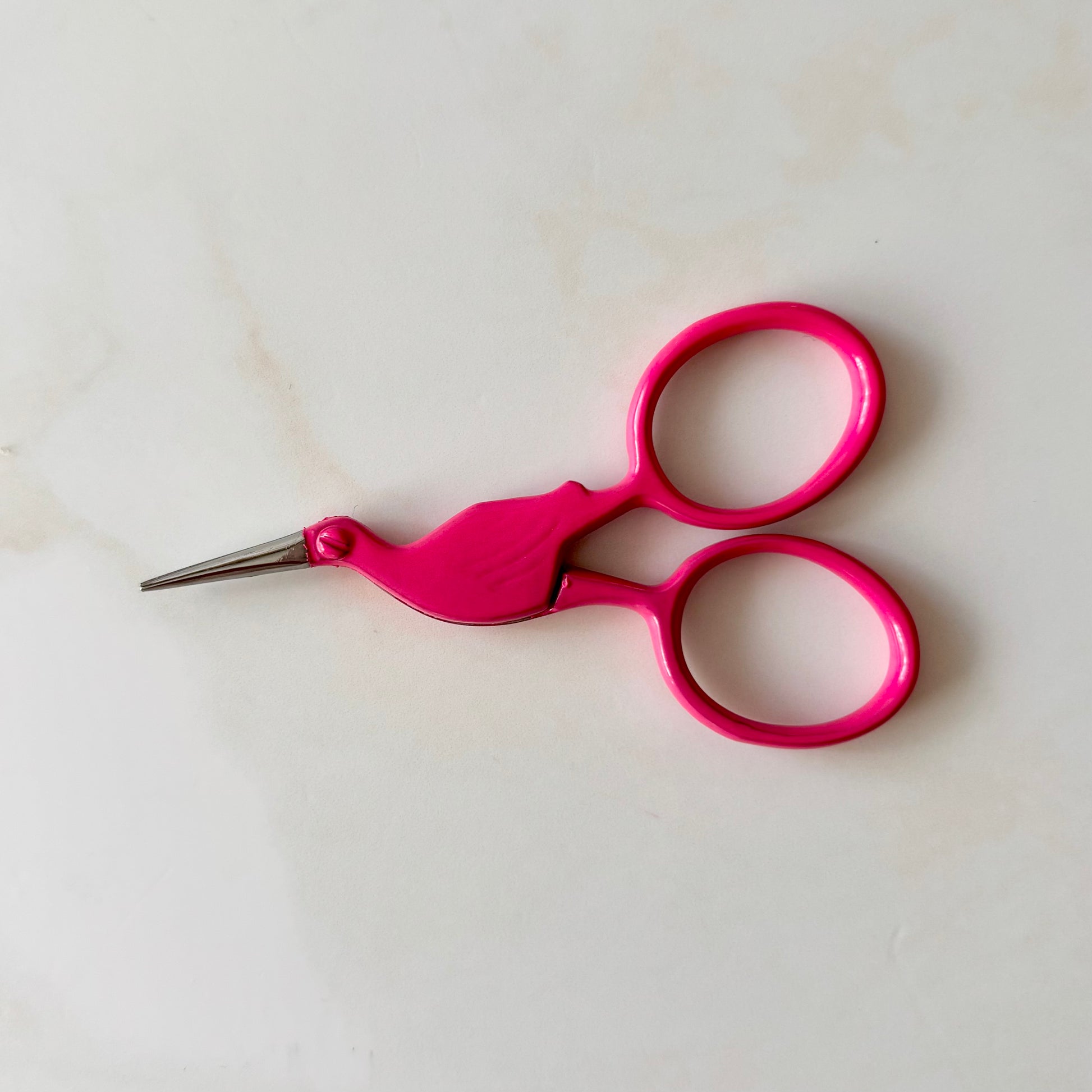 Pink scissors on a white background