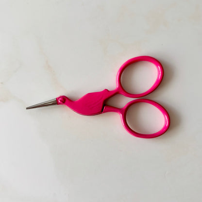 Pink scissors on a white background