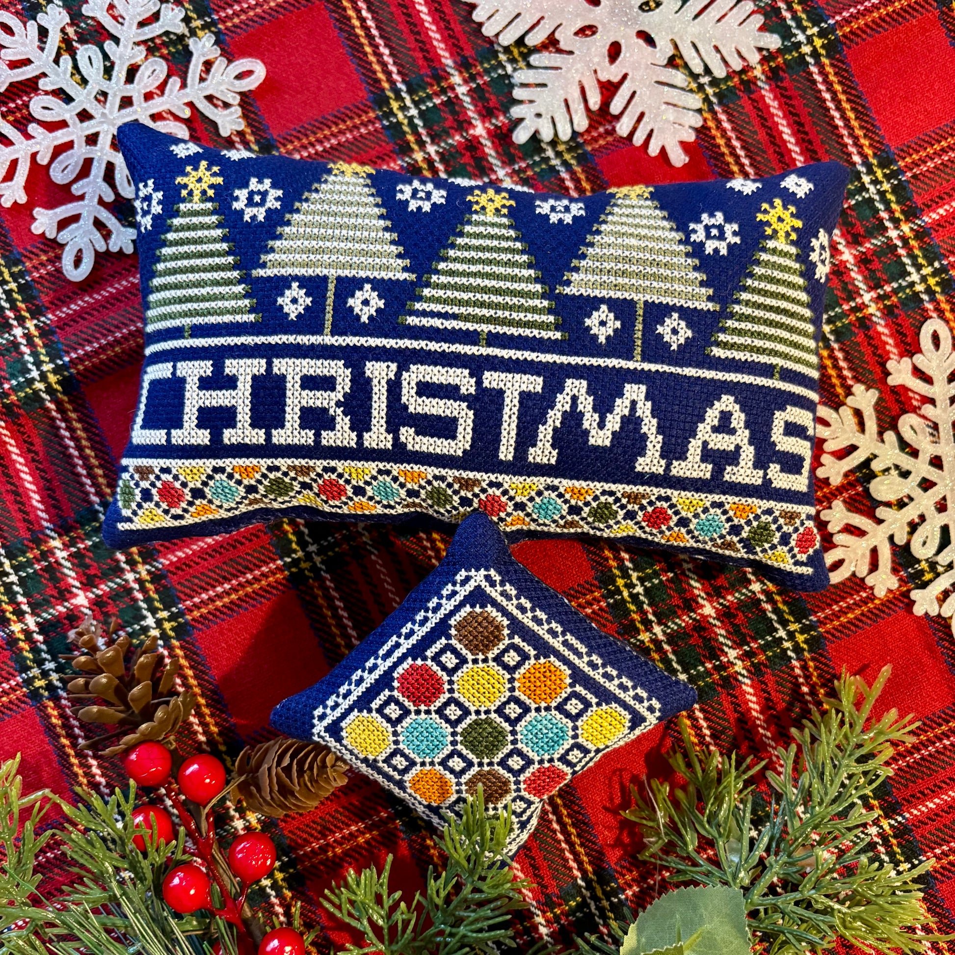 Decorative Christmas pillow with festive design on a plaid fabric background.