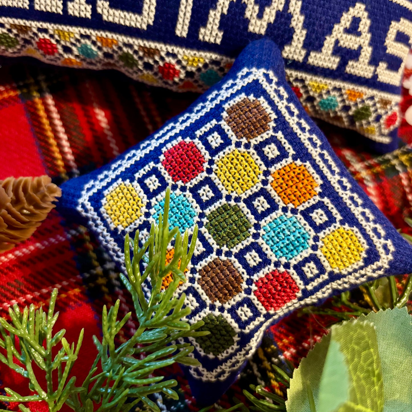 Decorative pillow with colorful geometric pattern on a plaid fabric background