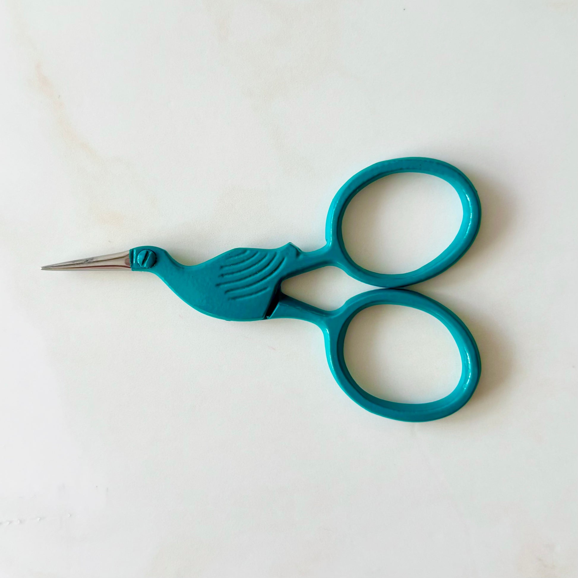 Teal bird-shaped scissors on a white background