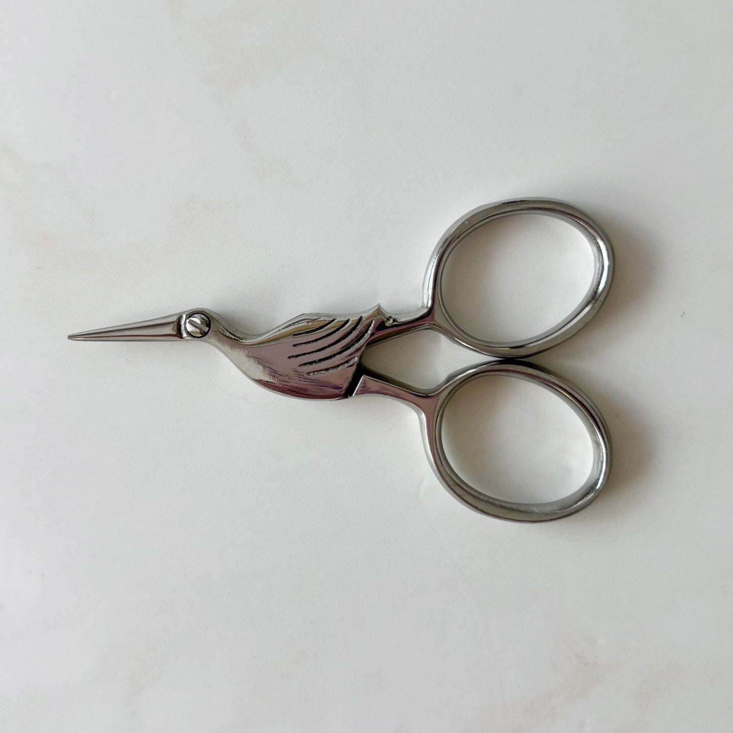 Pair of silver embroidery scissors on a white background