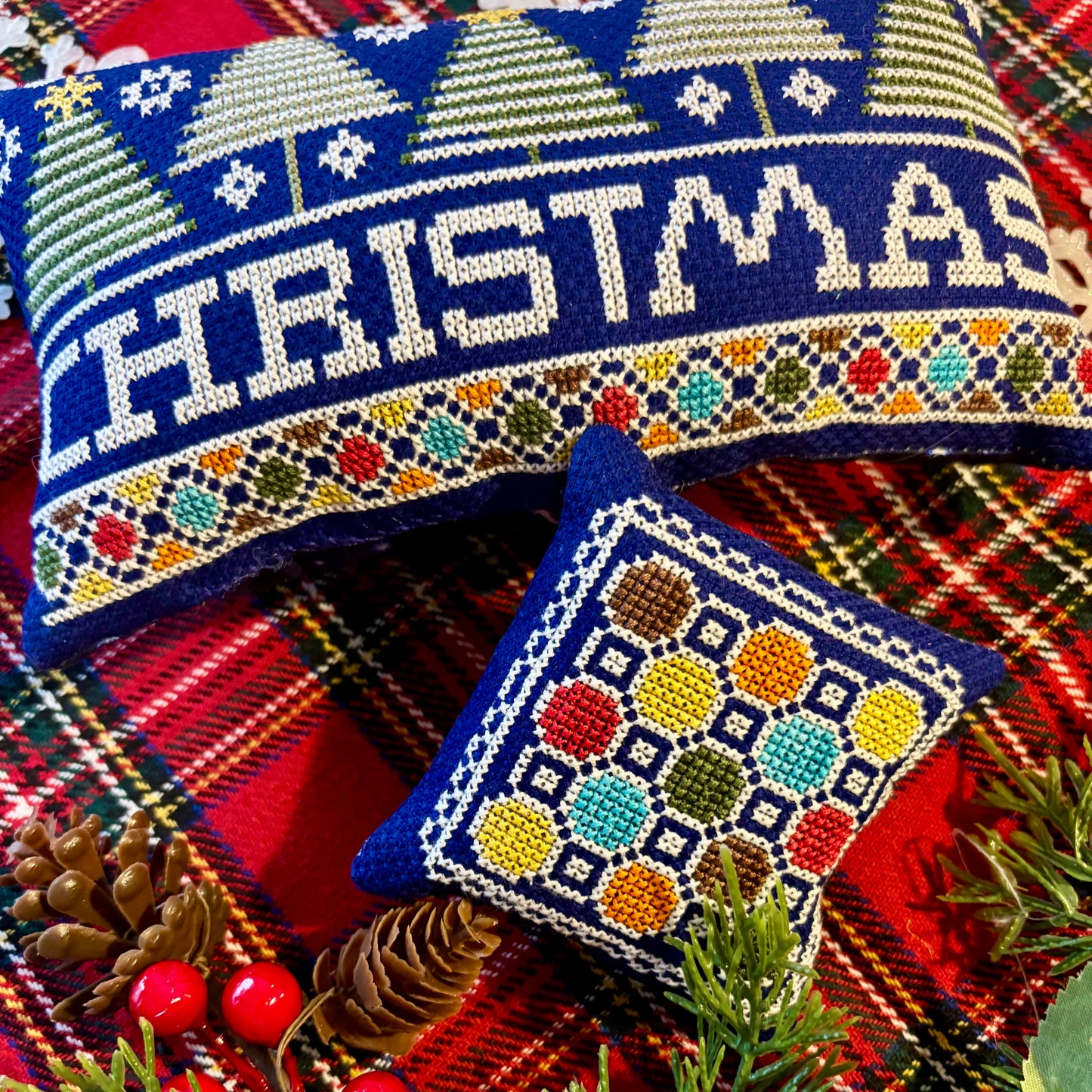 Decorative Christmas pillow with 'Christmas' text on a plaid fabric background.