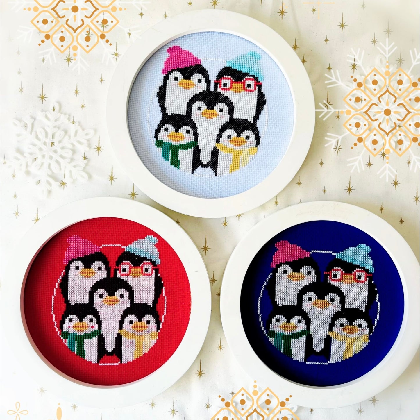 Three circular cross-stitch patterns of penguins on a decorative background with snowflakes.