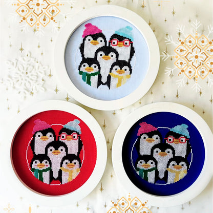 Three circular cross-stitch patterns of penguins on a decorative background with snowflakes.