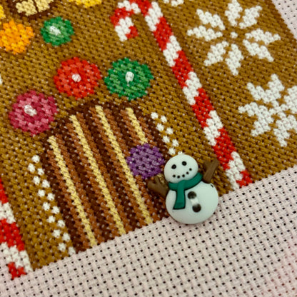 Close-up of a cross-stitched gingerbread house with candy canes and snowflakes.