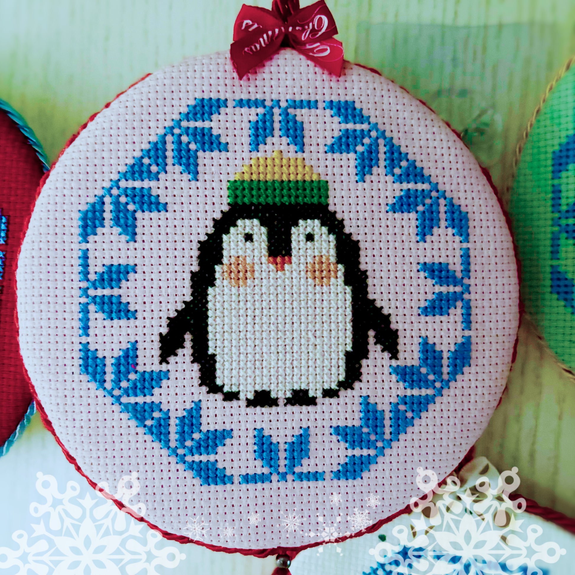 Cross-stitched penguin design on a hoop with blue floral pattern