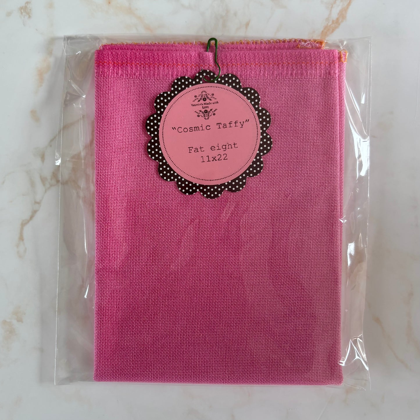 Pink fabric package with a label on a marble surface