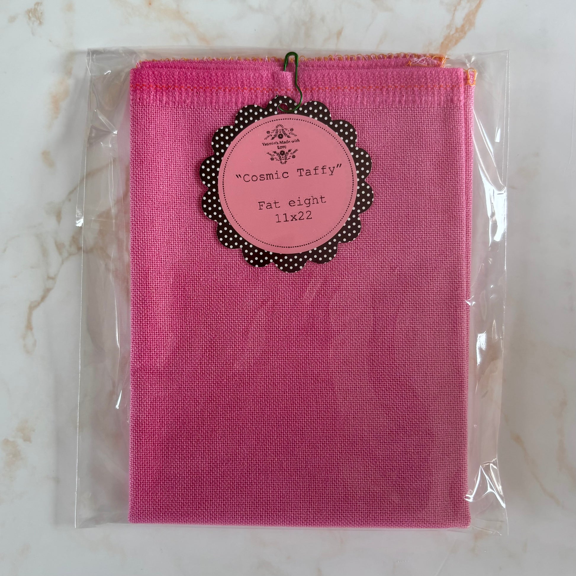 Pink fabric package with a label on a marble surface