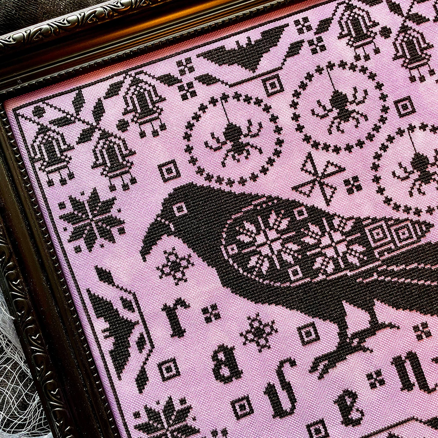 Raven cross-stitch pattern featuring black bird and decorative foliage