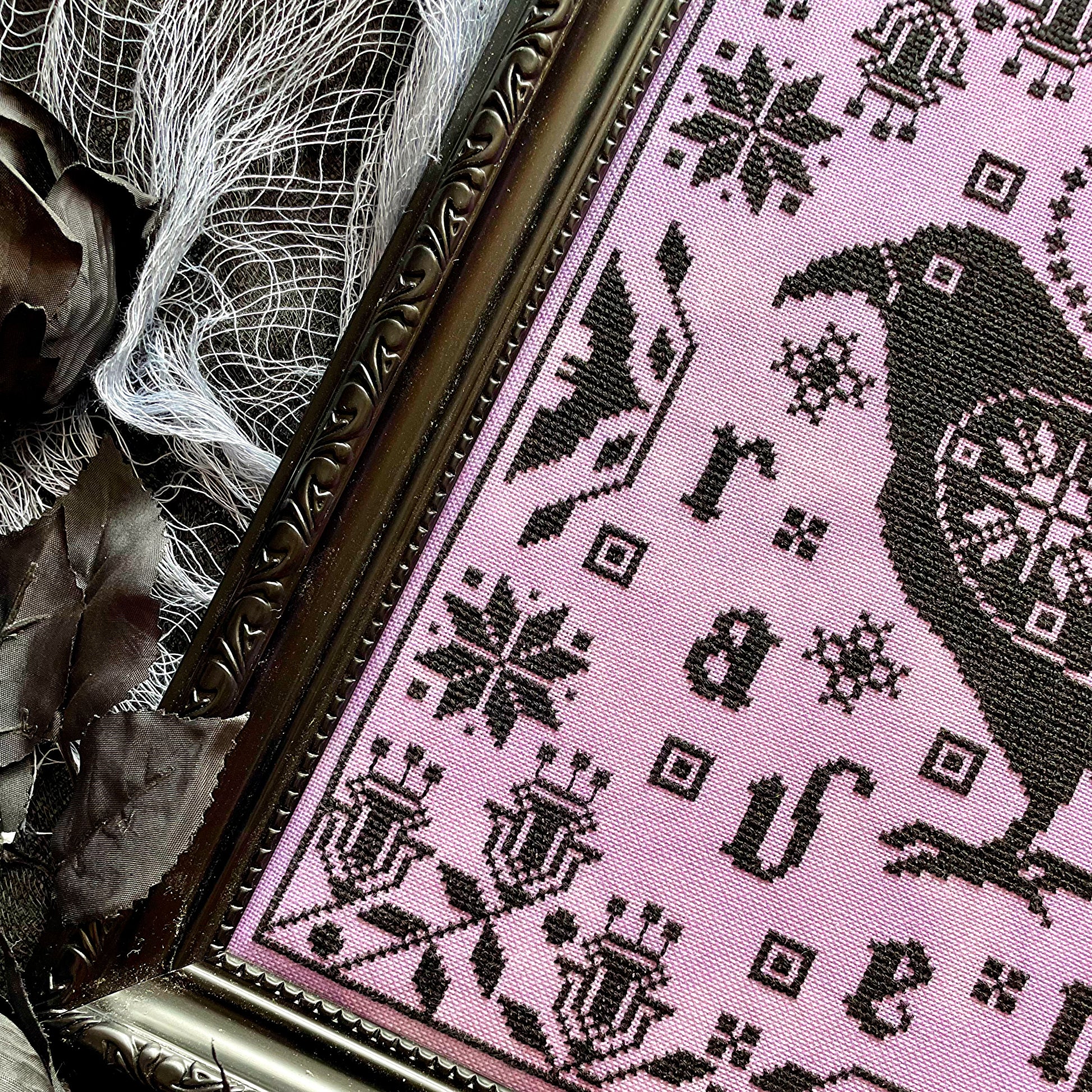 Raven cross-stitch pattern featuring black bird and decorative foliage