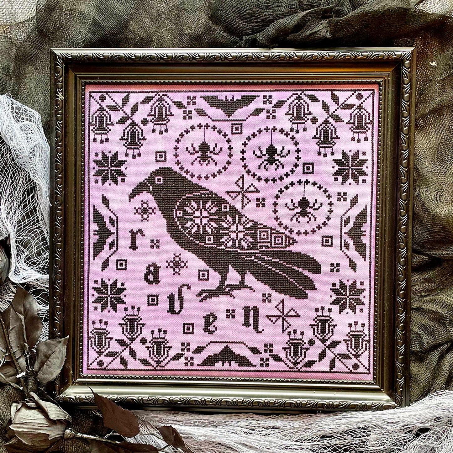 Raven cross-stitch pattern featuring black bird and decorative foliage