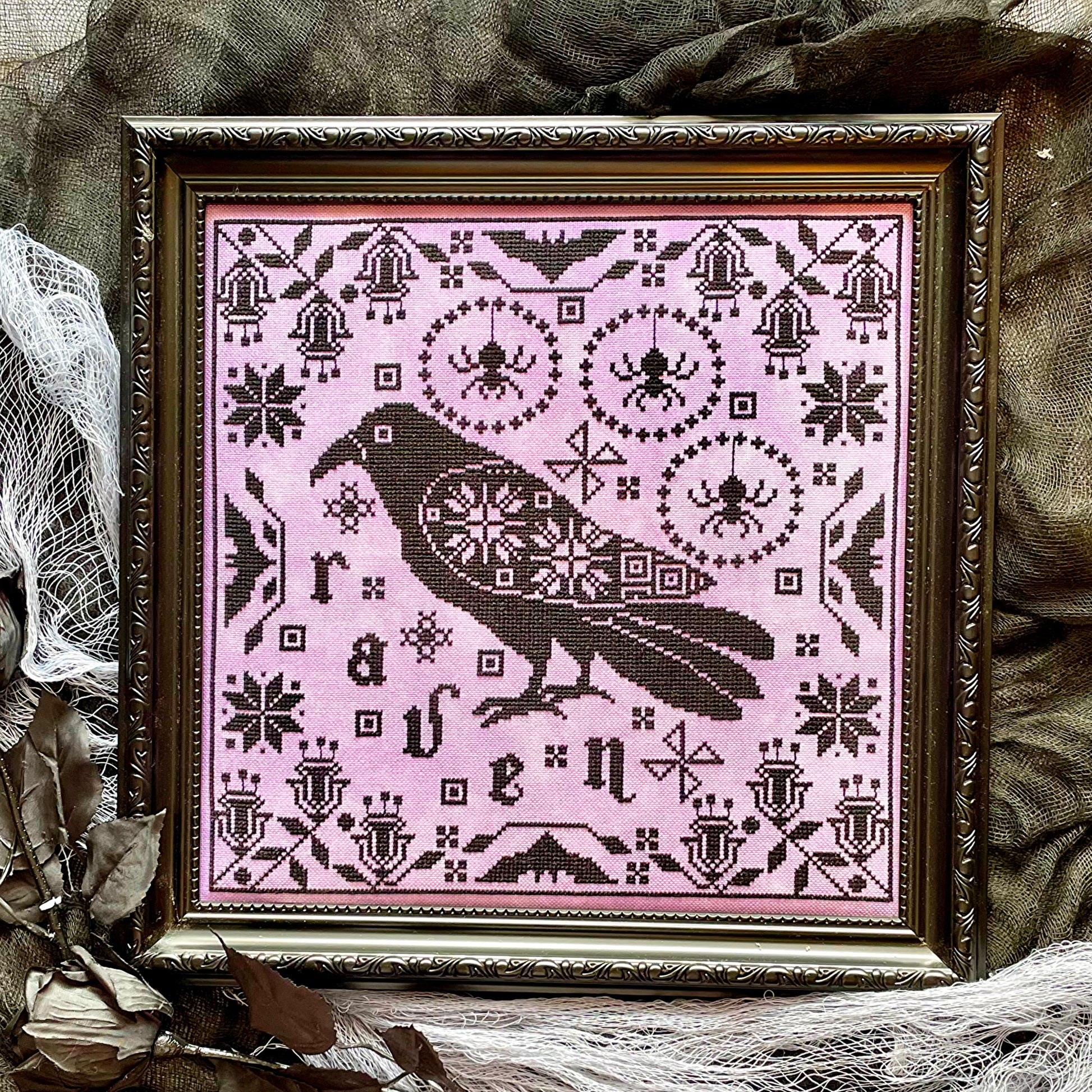 Raven cross-stitch pattern featuring black bird and decorative foliage
