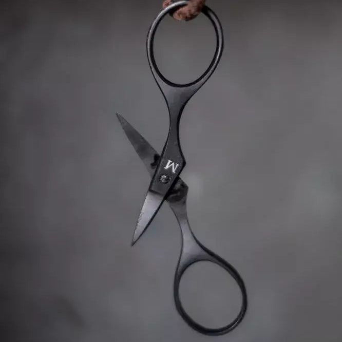 Pair of black-handled scissors hanging on a dark background