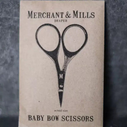 Card with illustration of scissors and text 'Merchant & Mills Draper Baby Bow Scissors' on a textured background