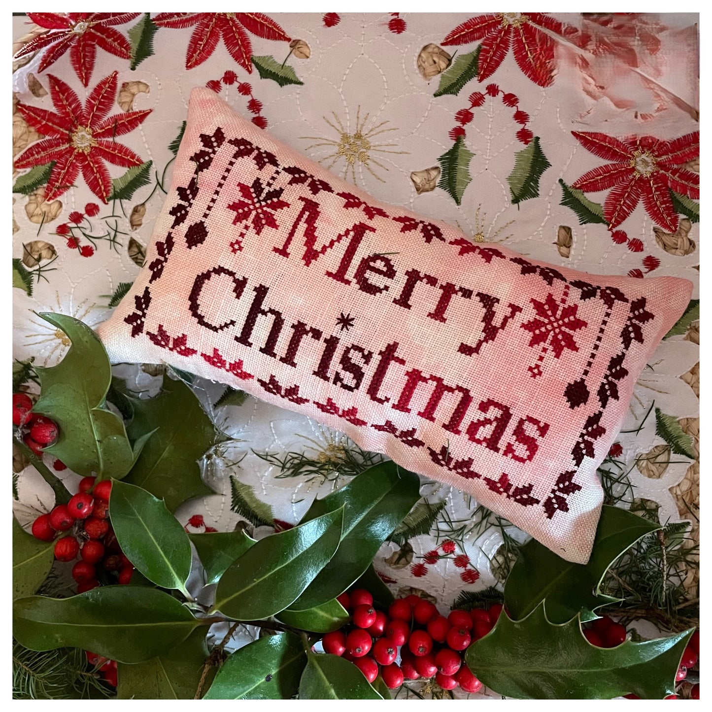 Decorative pillow with 'Merry Christmas' text on a festive background with poinsettias and holly.