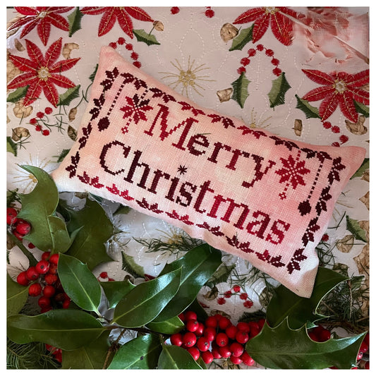 Decorative pillow with 'Merry Christmas' text on a festive background with poinsettias and holly.