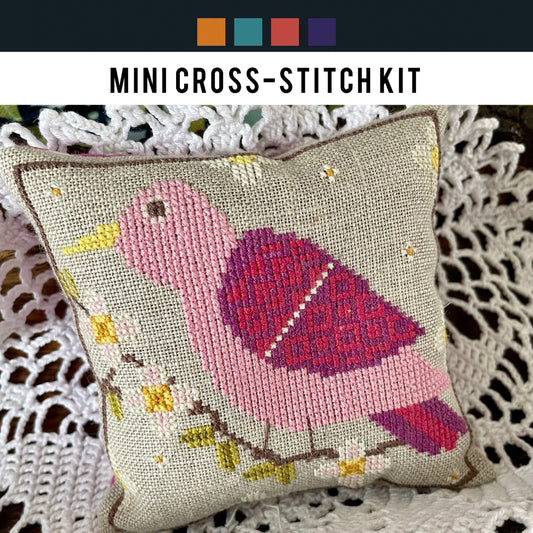 Cross-stitched bird design on a pillow with a crochet background