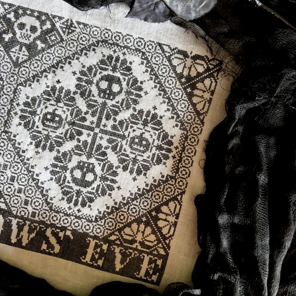 Patterned fabric with skull designs and 'Halloween Eve' text on a dark background