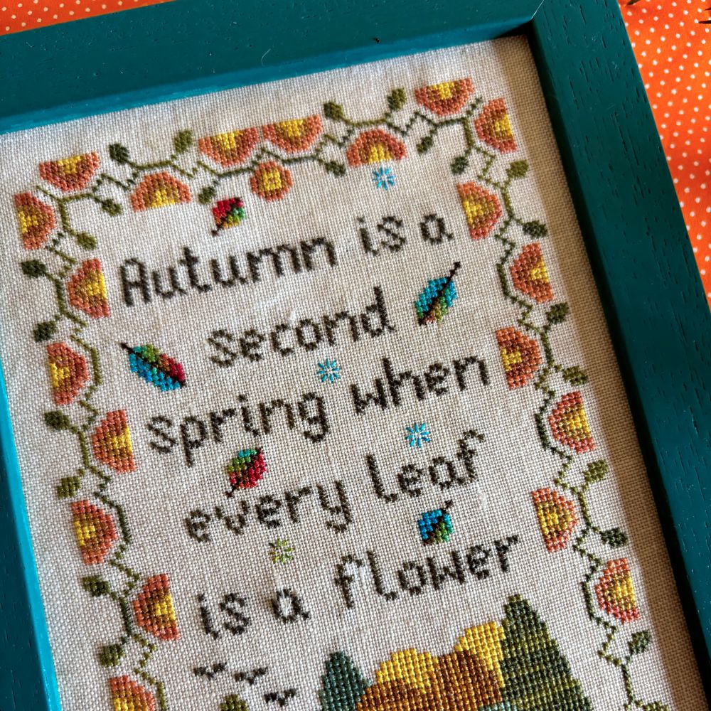 Cross-stitched piece with autumn-themed text and leaf designs.