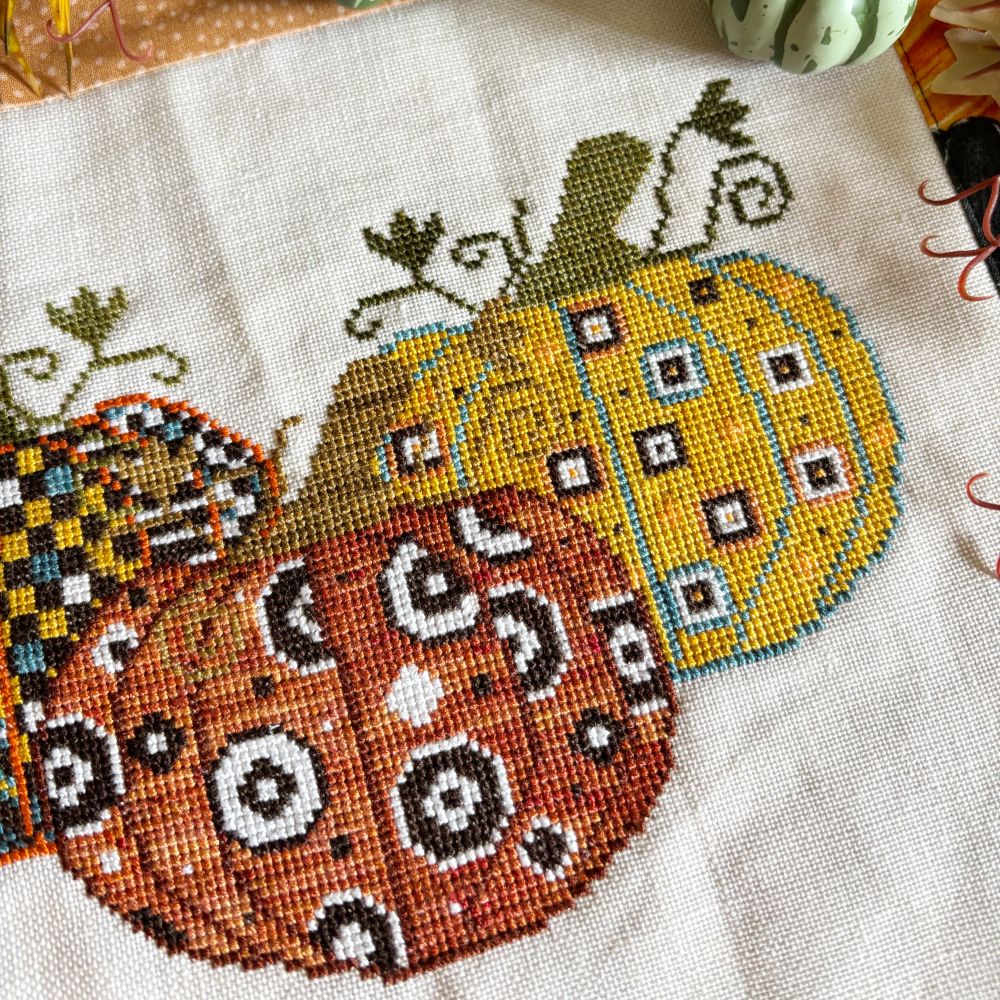 Cross-stitch pattern titled Patchwork Pumpkins showing a quilt-inspired grid of orange