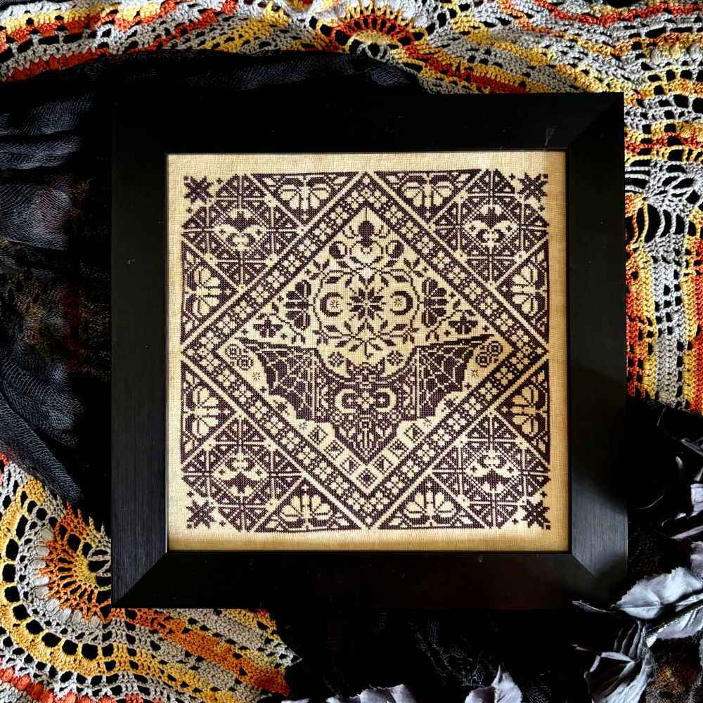 Decorative framed artwork with geometric pattern on a textured fabric background