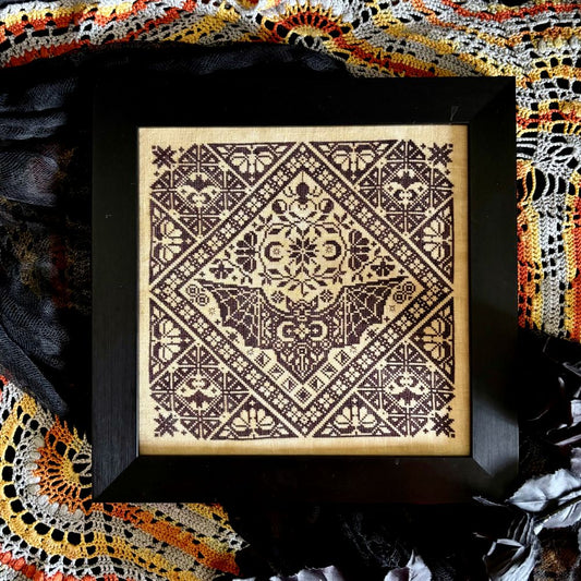 Decorative framed artwork with geometric pattern on a textured fabric background